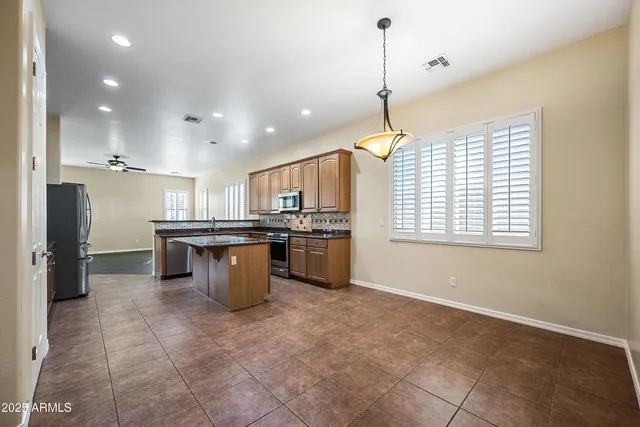 a kitchen with kitchen island stainless steel appliances a sink a counter top space cabinets and a window