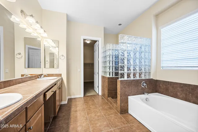 a spacious bathroom with a tub sink and mirror