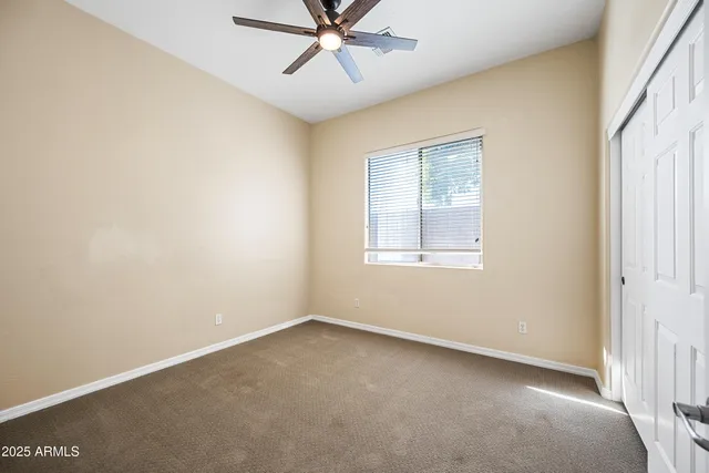 an empty room with a window and a fan