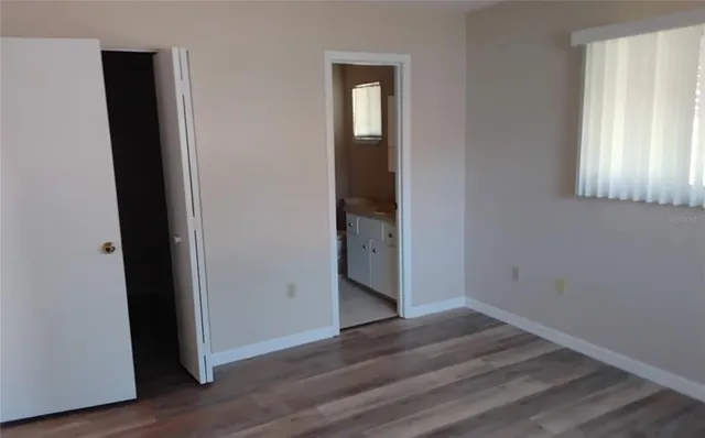 a view of an empty room with wooden floor and closet