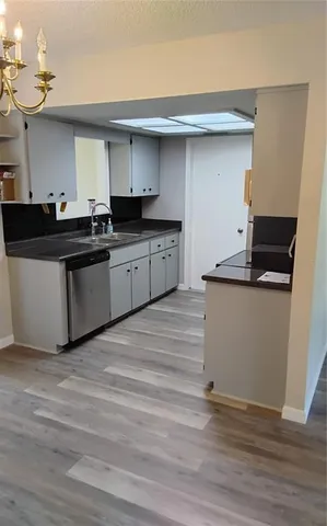 a kitchen with granite countertop a white cabinets and wooden floor