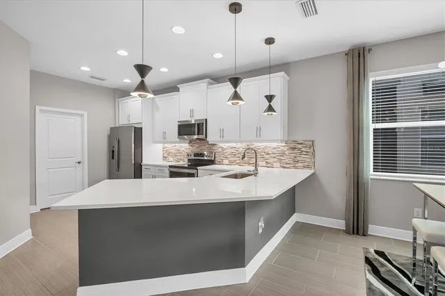 a kitchen with kitchen island a sink stainless steel appliances and a window