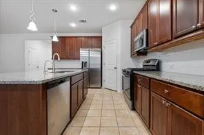 a kitchen with stainless steel appliances granite countertop a stove a sink a refrigerator and a microwave