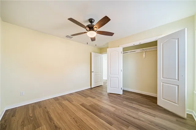 a view of a big room with wooden floor a ceiling fan and closet