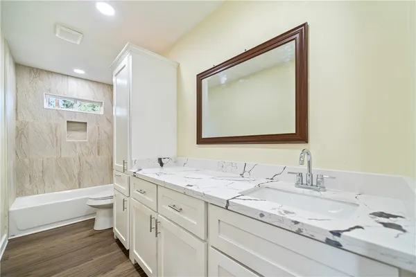 a bathroom with a granite countertop sink mirror and a toilet