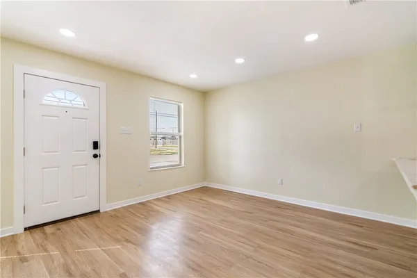 a view of an empty room with wooden floor and a window