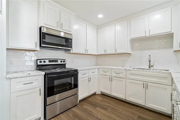 a kitchen with white cabinets stainless steel appliances and sink