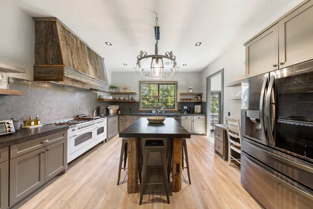 a kitchen with granite countertop a stove a sink dishwasher a refrigerator and cabinets with wooden floor