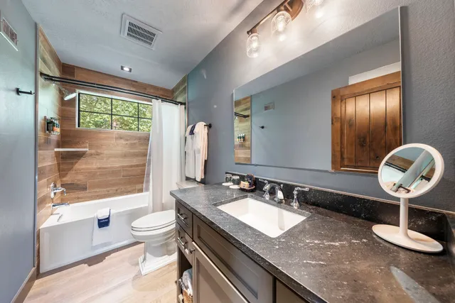 a bathroom with a granite countertop sink a toilet a mirror and shower