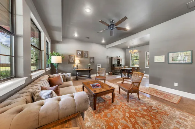 a living room with furniture a rug kitchen view and a large window