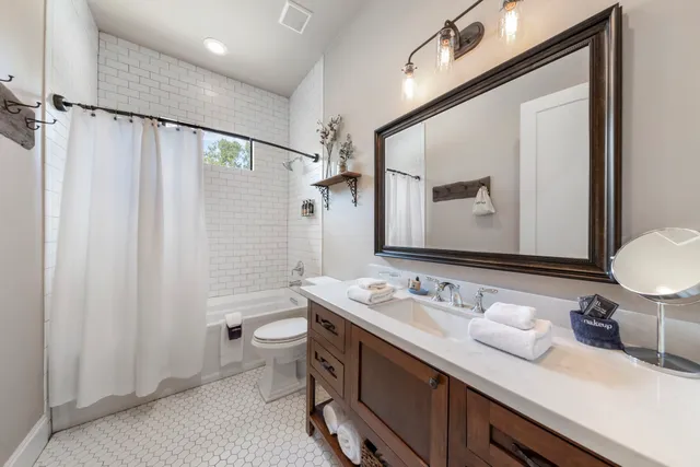 a bathroom with a double vanity sink toilet mirror and shower