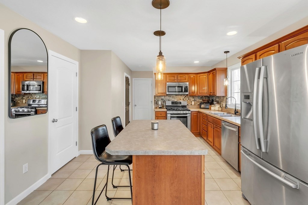 29 Bruce Street Springfield, MA 01119 - Photo 11 of 42 a kitchen with stainless steel appliances kitchen island granite countertop a refrigerator a stove top oven a sink dishwasher and a dining table with wooden floor