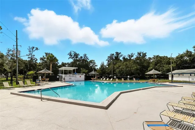 a view of a swimming pool with lawn chairs and a big yard