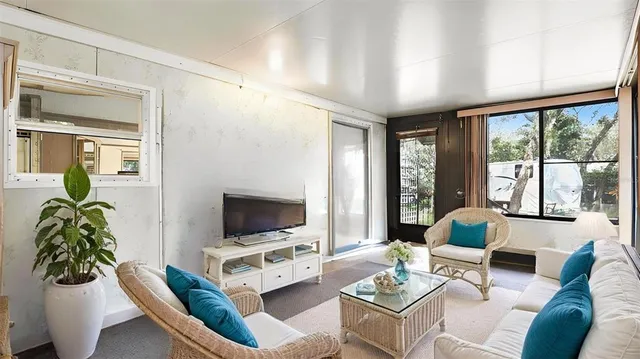 a living room with furniture a flat screen tv and a large window