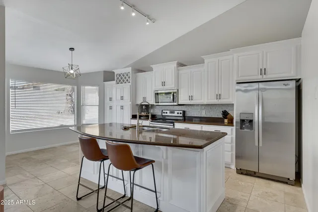 a kitchen with kitchen island a counter top space a sink stainless steel appliances and cabinets