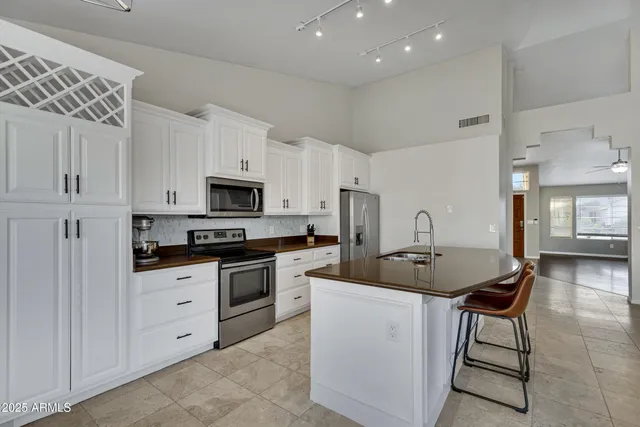 a kitchen with stainless steel appliances kitchen island granite countertop a stove a sink a refrigerator a microwave and cabinets