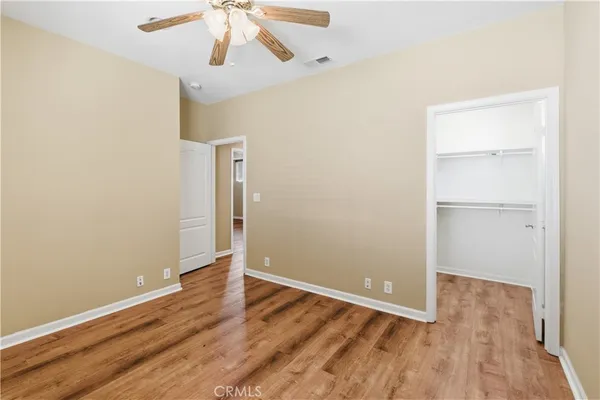an empty room with wooden floor closet and windows