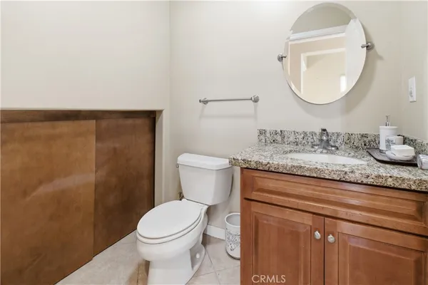 a bathroom with a granite countertop toilet sink mirror and vanity