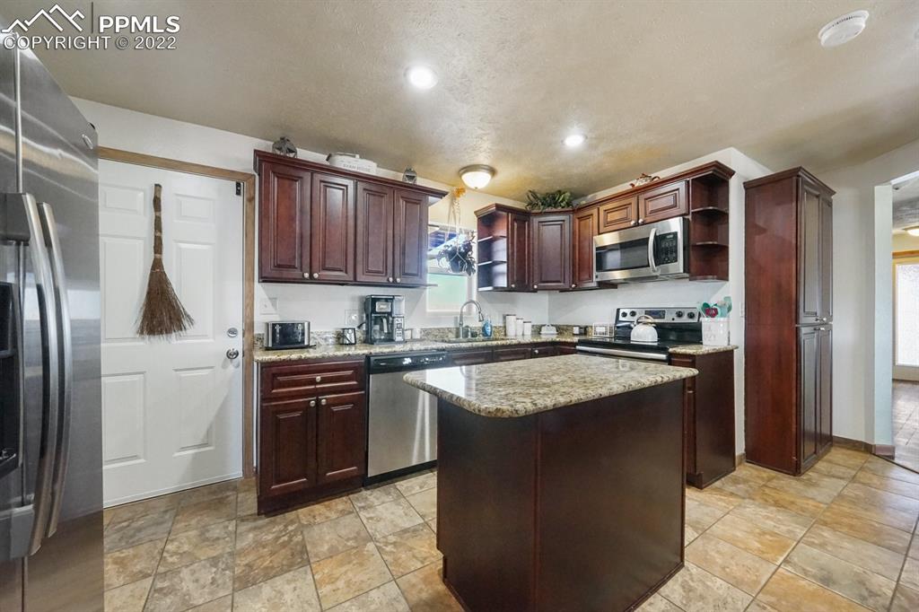 6260 Night Train Lane Yoder, CO 80864 - Photo 16 of 24 a kitchen with stainless steel appliances granite countertop a stove top oven a sink and a refrigerator