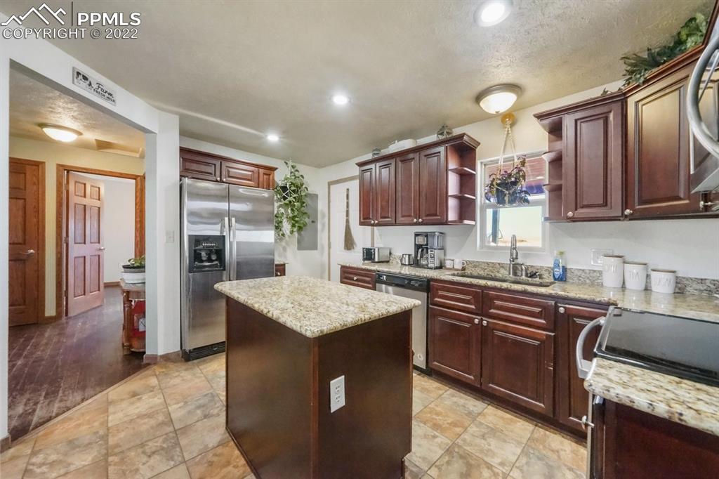 6260 Night Train Lane Yoder, CO 80864 - Photo 19 of 24 a kitchen with stainless steel appliances granite countertop a sink stove microwave and refrigerator