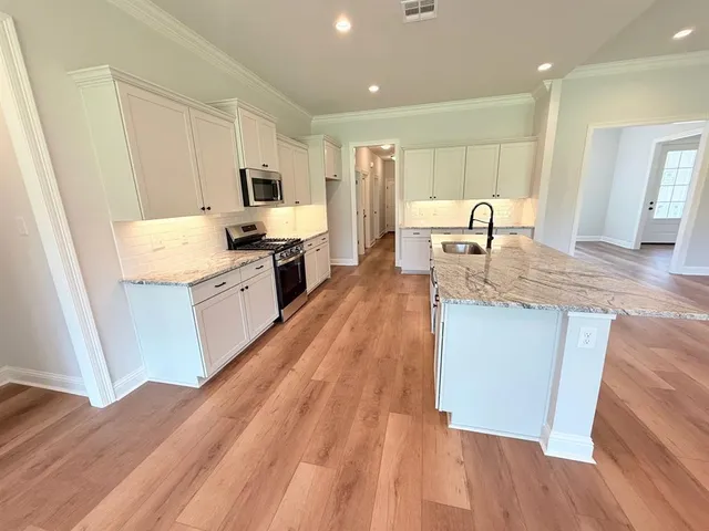a large kitchen with stainless steel appliances granite countertop a lot of counter space and wooden floors