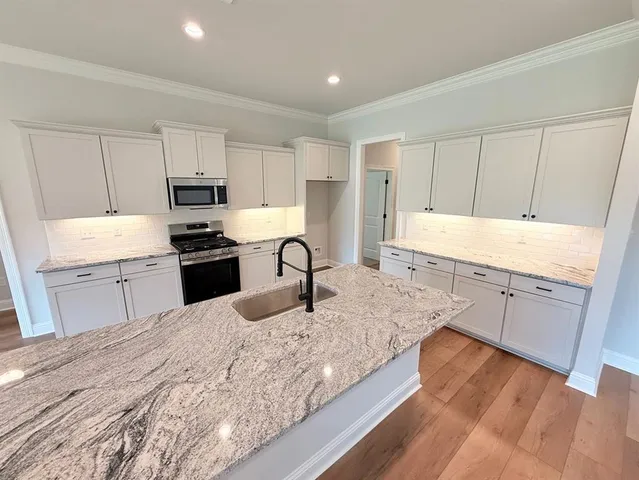 a kitchen with stainless steel appliances granite countertop a sink stove and refrigerator