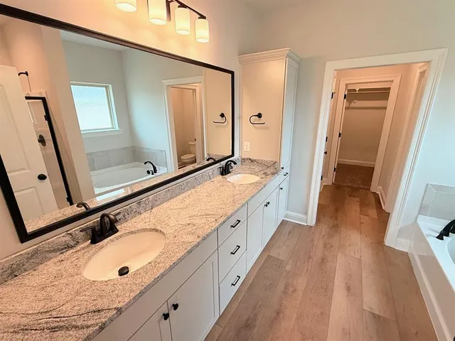 a spacious bathroom with a granite countertop double vanity sink and a mirror