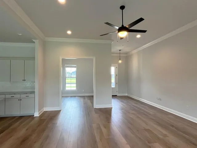 a view of an empty room with wooden floor and a ceiling fan