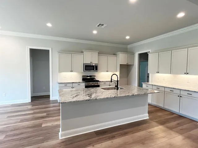 a large kitchen with granite countertop a large counter top space a sink stainless steel appliances and cabinets