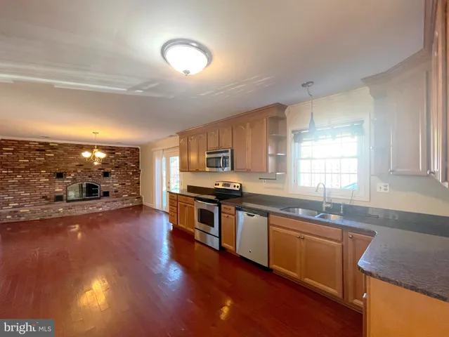 a kitchen with stainless steel appliances granite countertop a sink stove and wooden floor