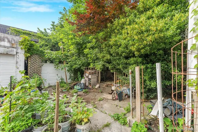 a backyard of a house with table and chairs potted plants and large tree