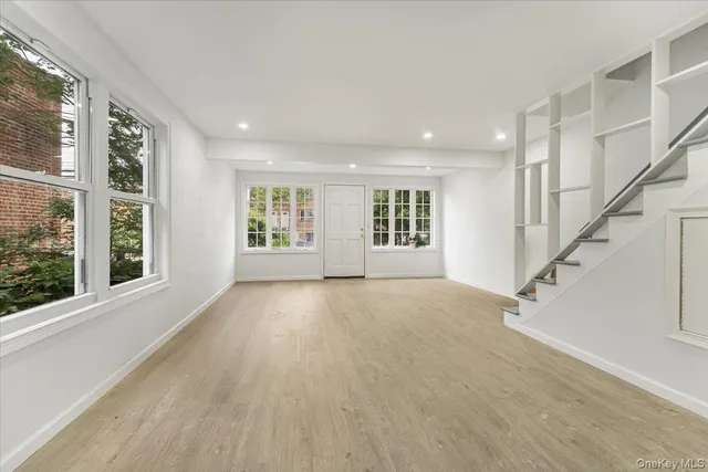 a view of an empty room with a window and wooden floor