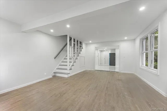 a view of an empty room with wooden floor and stairs