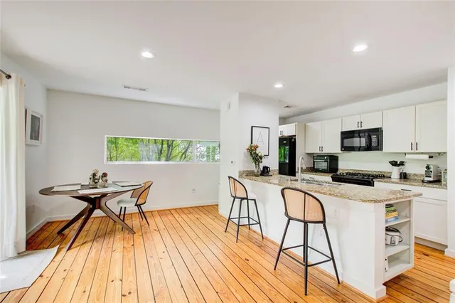 a kitchen with stainless steel appliances a kitchen island hardwood floor sink stove dining table and chairs