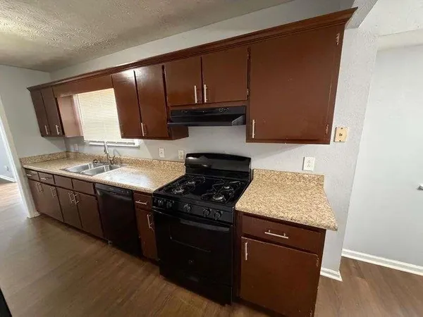 a kitchen with granite countertop wooden cabinets and a stove top oven