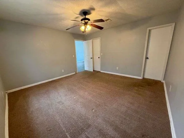 an empty room with a chandelier fan and windows
