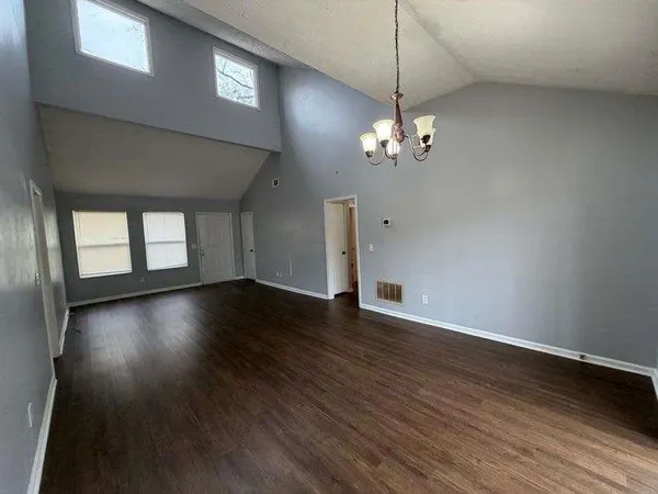 a view of a livingroom with a large window wooden floor and a chandelier