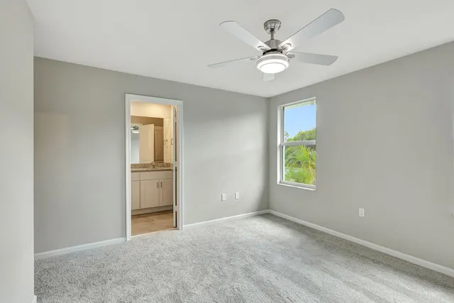 an empty room with windows and ceiling fan