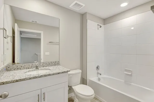 a bathroom with a granite countertop sink a toilet and bathtub