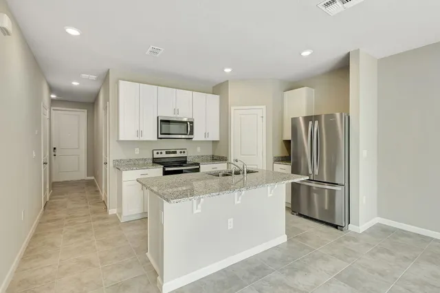 a kitchen with stainless steel appliances granite countertop a refrigerator a stove a sink a microwave and white cabinets