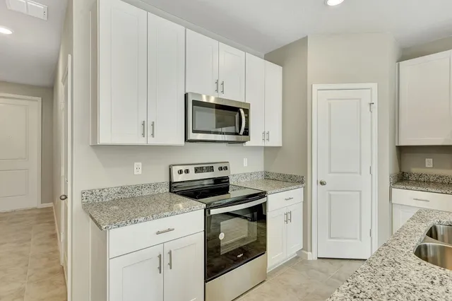 a kitchen with granite countertop white cabinets and white appliances
