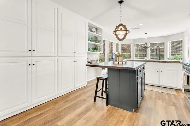 a kitchen with kitchen island granite countertop wooden floors and white cabinets