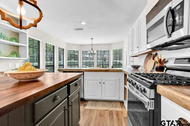 a kitchen with stainless steel appliances granite countertop a stove a sink and a microwave