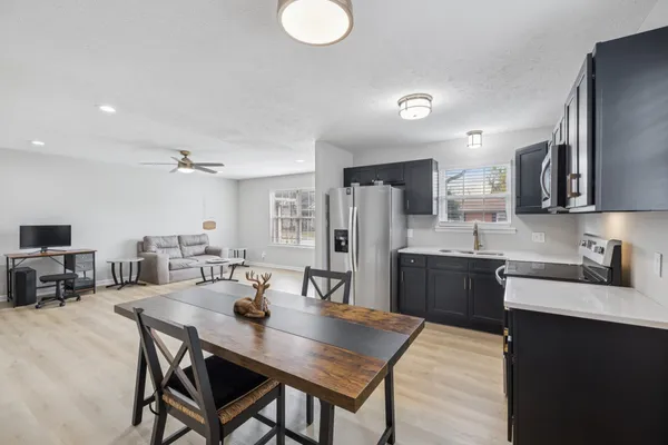 a kitchen with stainless steel appliances granite countertop a dining table chairs stove refrigerator and cabinets