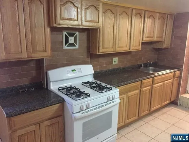 a kitchen with granite countertop a stove sink and cabinets