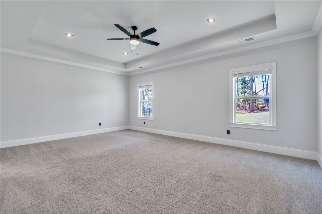 226 Holly Br Road Piedmont, SC 29673 - Photo 20 of 44 A spacious primary bedroom features tray ceilings, recessed lighting, and a ceiling fan for ultimate comfort.