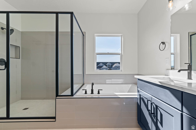 562 West Coyote Rdg Road Grantsville, UT 84029 - Photo 21 of 27 Modern bathroom featuring a glass-enclosed shower with matte black fixtures, a soaking tub, and a vanity with a white countertop and blue cabinetry
