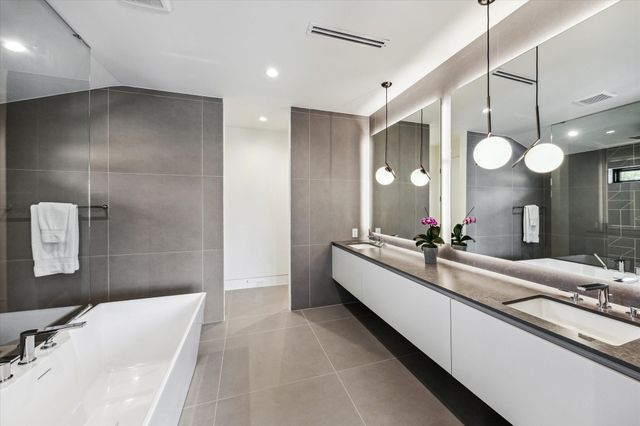 a bathroom with a double vanity sink mirror and bathtub