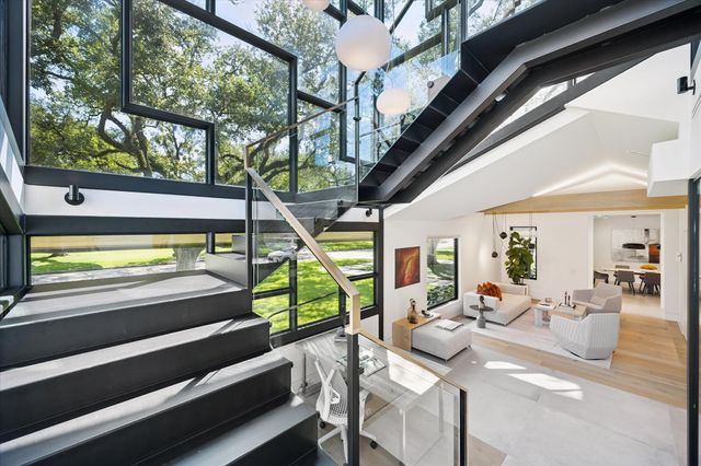 a view of a dining room with furniture a chandelier and large windows