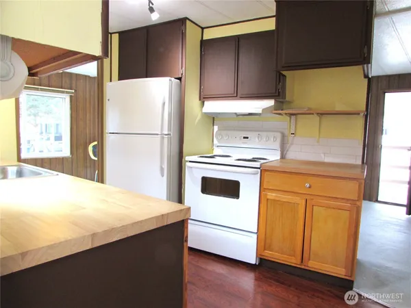 a kitchen with a refrigerator a stove a sink dishwasher and wooden floor